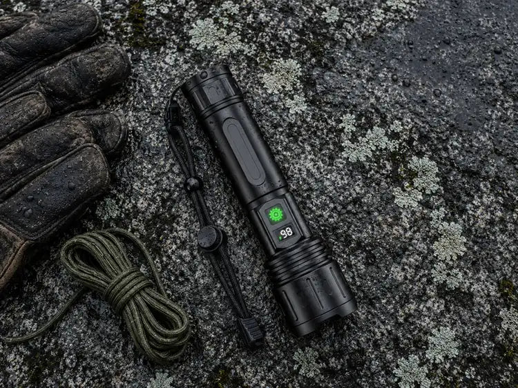 The flashlight on wet granite beside leather gloves and a coil of cord